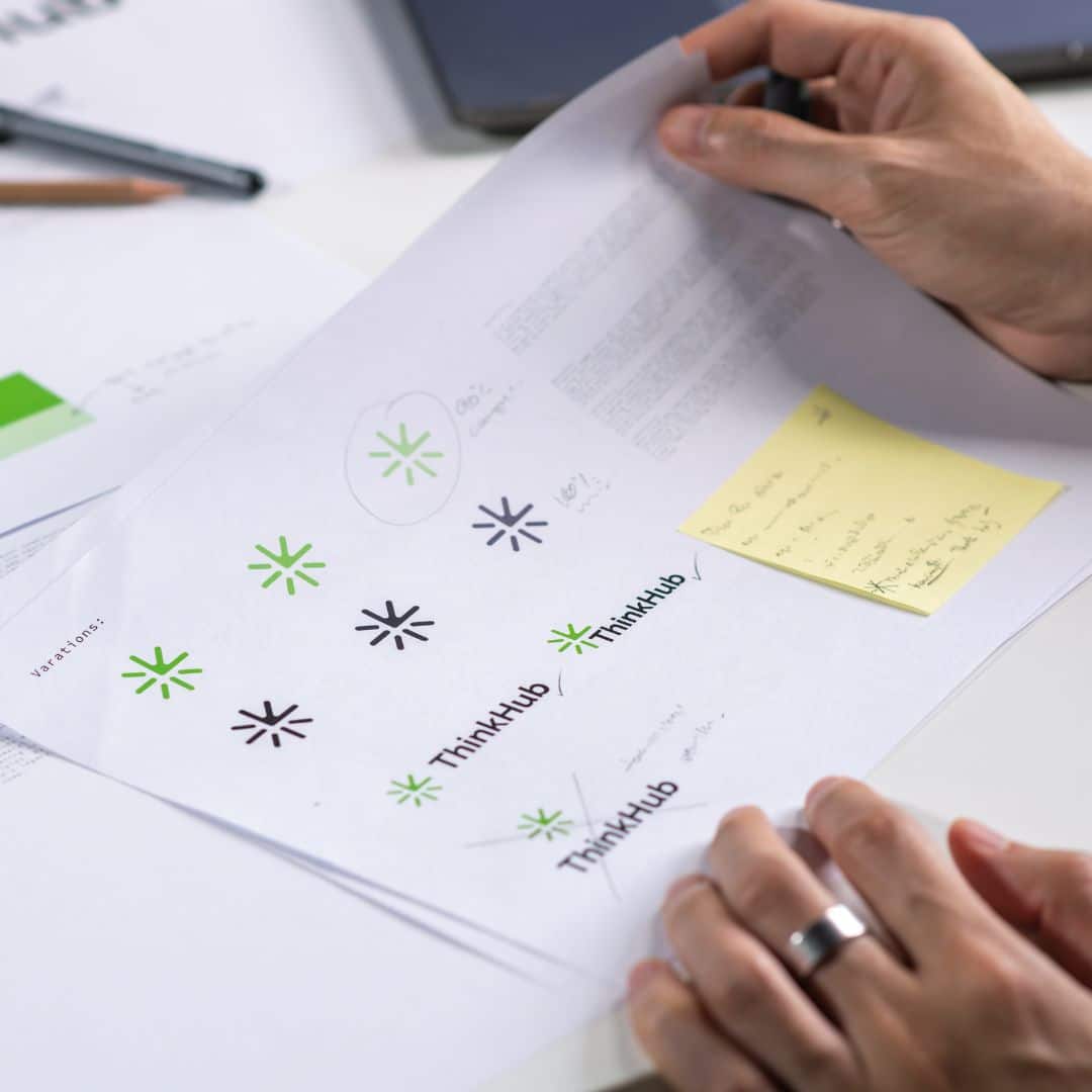 Close-up of logo design variations and brand identity sketches on paper with handwritten notes